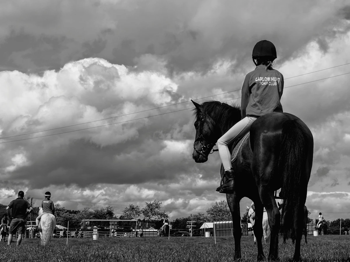 Black and white photo of a young rider on a dark horse