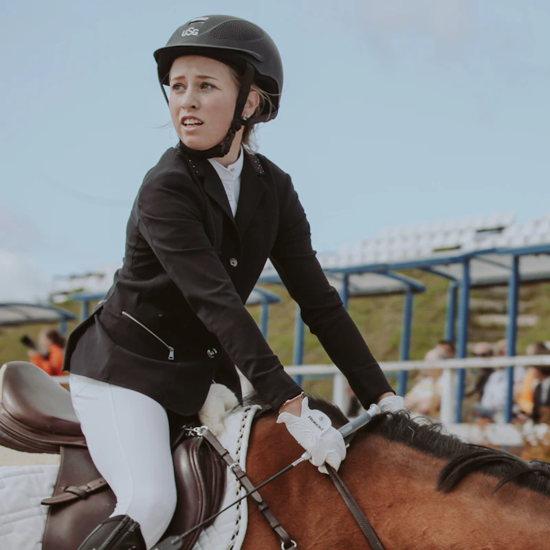 A rider in a helmet and black jacket in the saddle